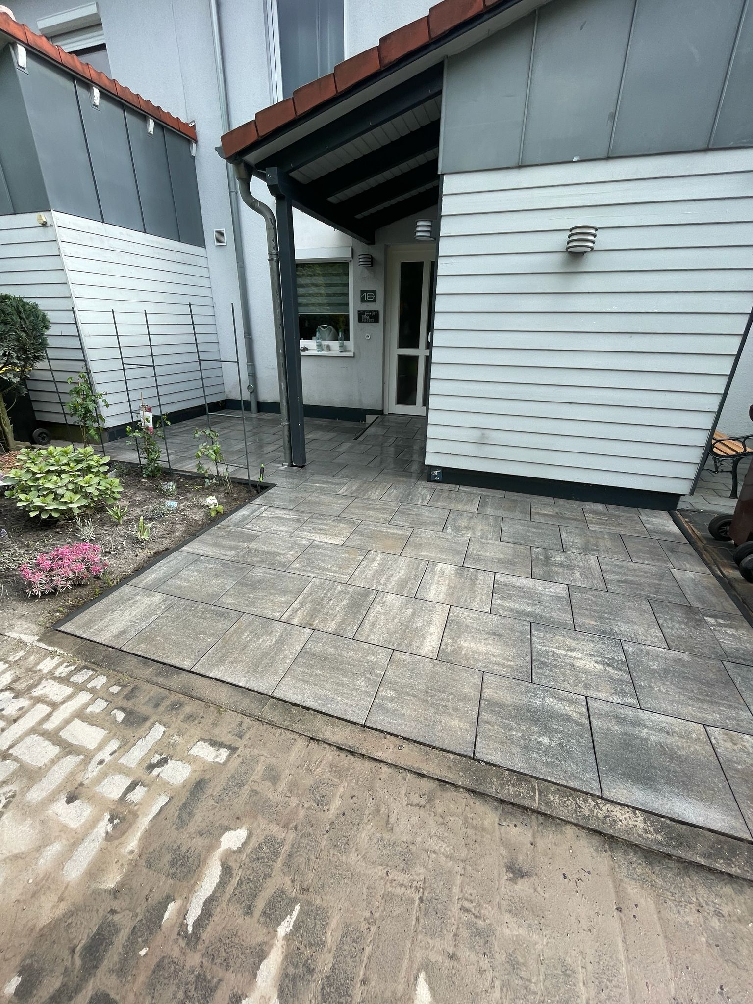Gepflasterter Eingangsbereich mit grauen Betonplatten vor einem Wohnhaus