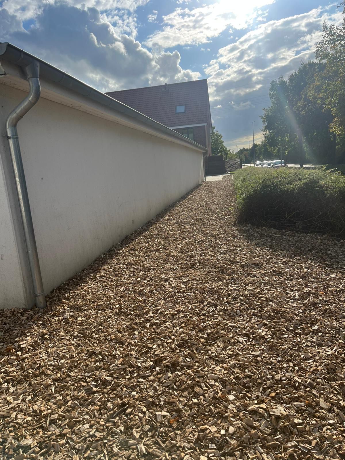 Hackschnitzelweg an einer Hauswand entlang