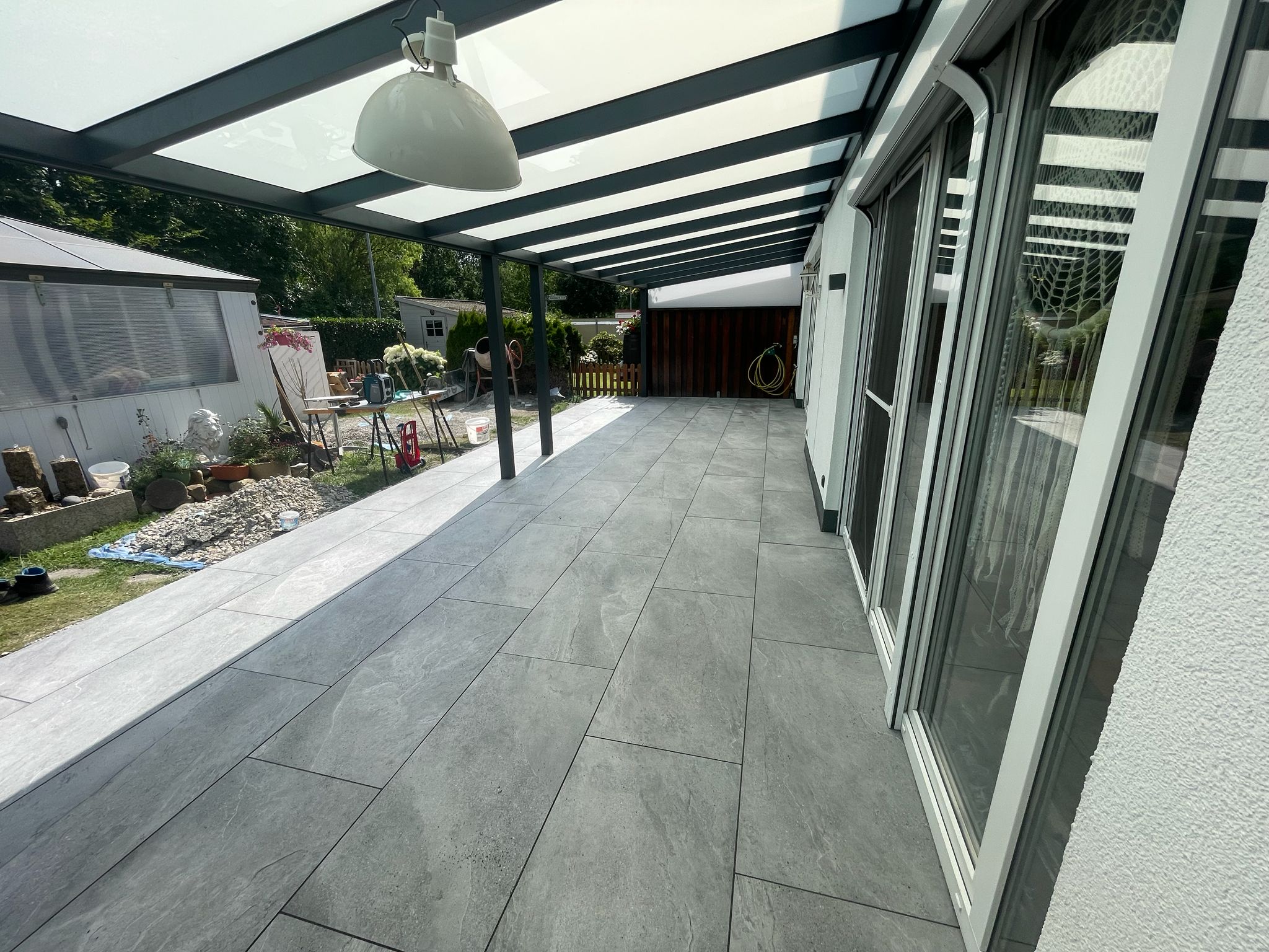 Überdachte Terrasse mit grauen Feinsteinzeug-Platten